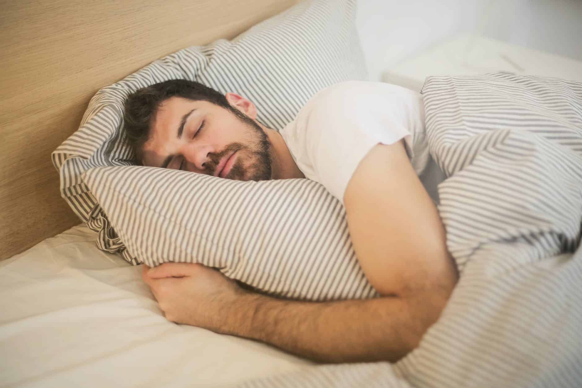 A man sleeping while holding a pillow in bed.